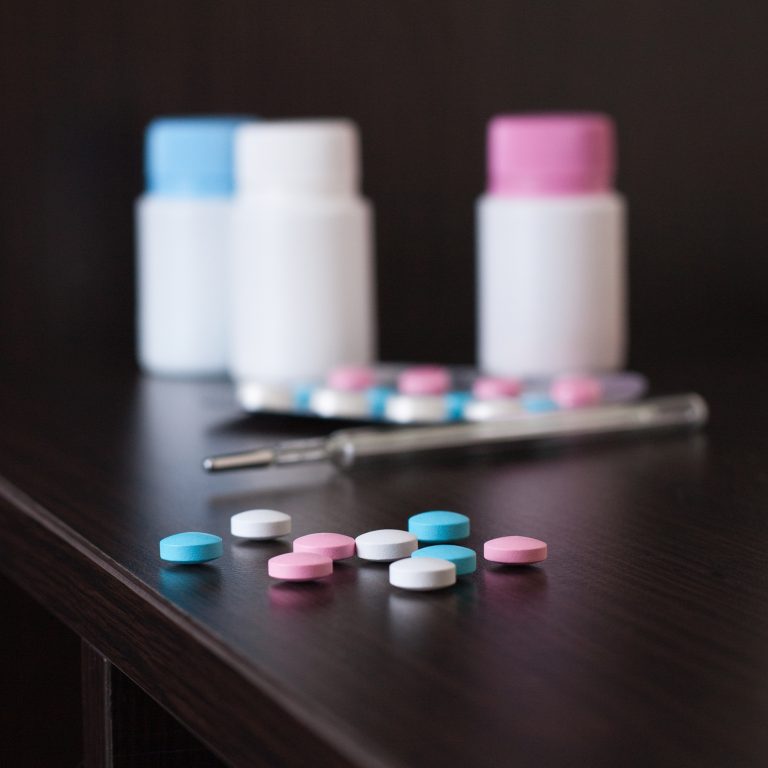 pills and thermometer on brown table
