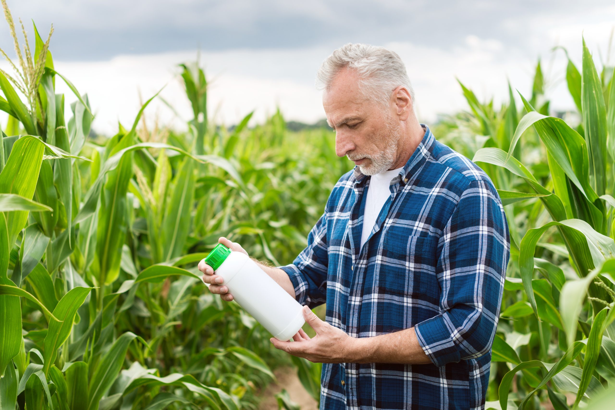 Middle aged farmer in a field holding a bottle with chemical fe